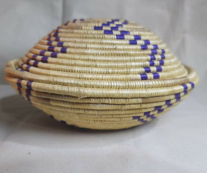 Handwoven raffia basket with matching lid and striking blue accents.