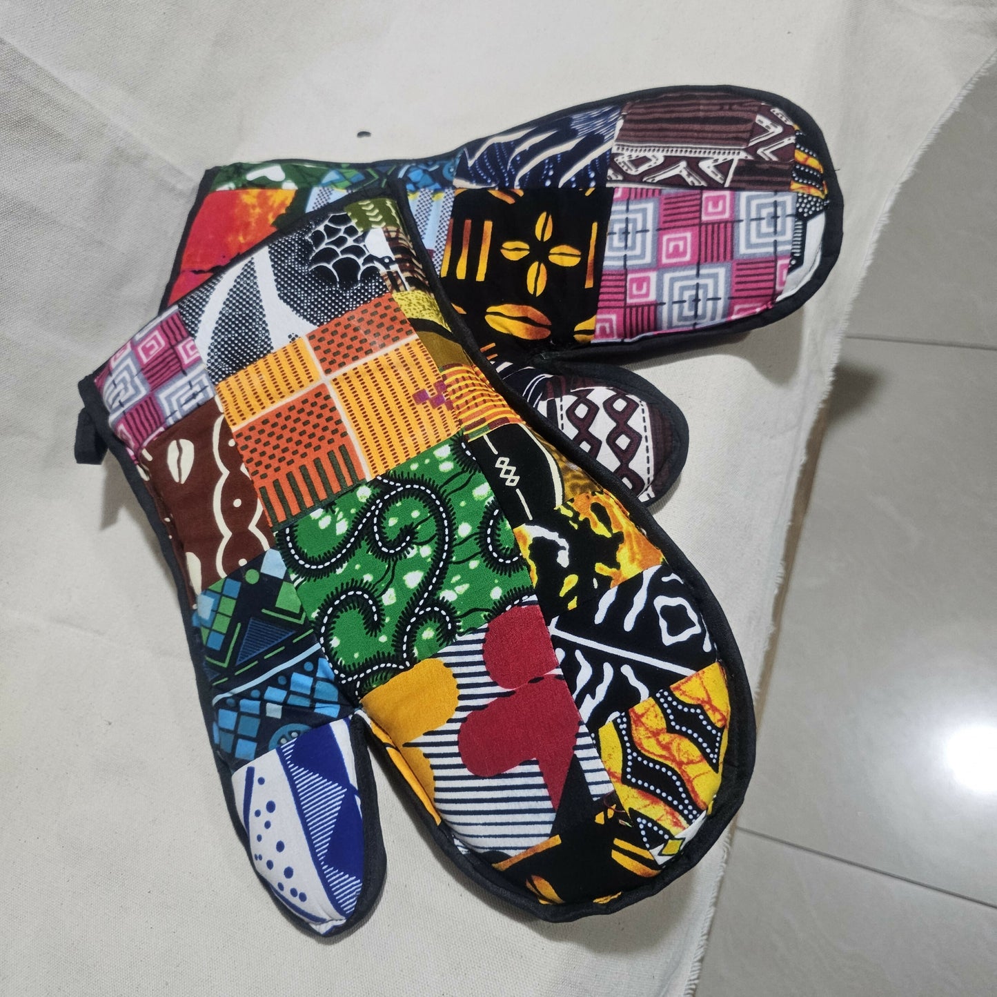 Colorful patterned oven mitts on a light tiled floor