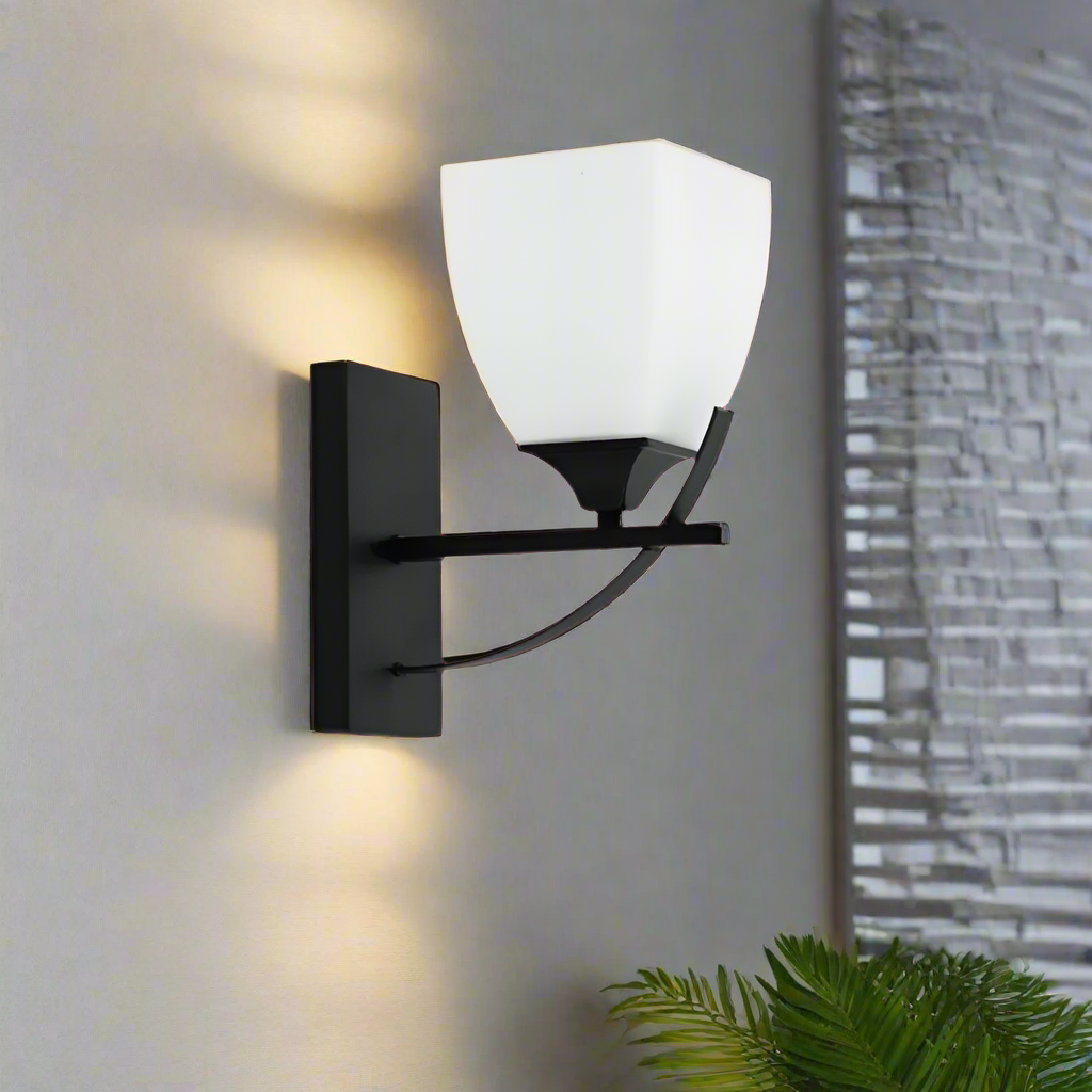 Matte Black & Frosted Glass Transitional Wall Sconce mounted on gray wall emitting soft warm light
