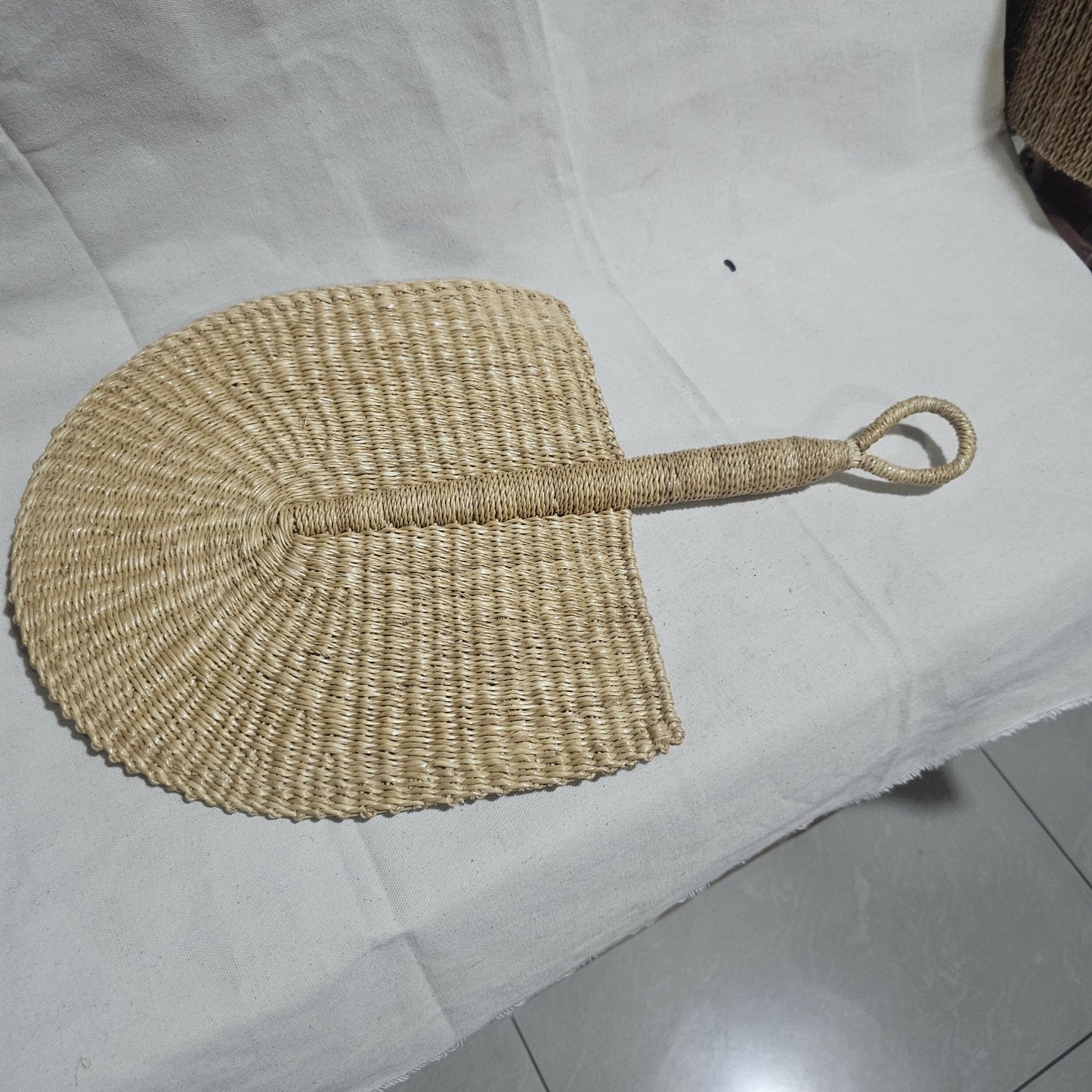 Woven fan with a handle on a white surface
