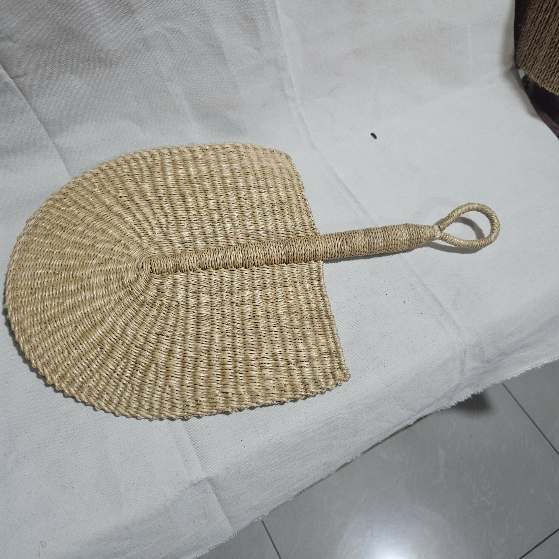 Woven fan with a handle on a white surface