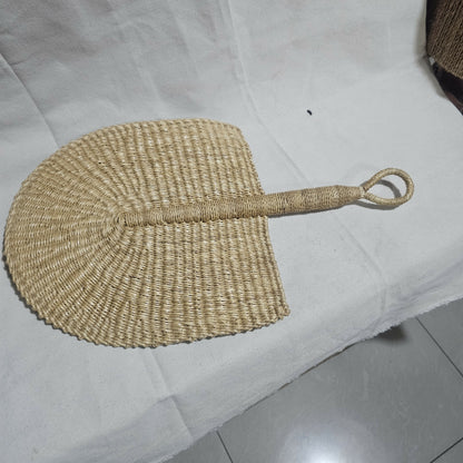 Woven fan with a handle on a white surface
