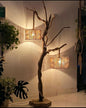 Floor lamp with natural branch design and two lampshades in a room setting.