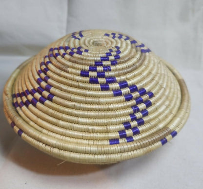 Handwoven raffia basket with matching lid and striking blue accents.