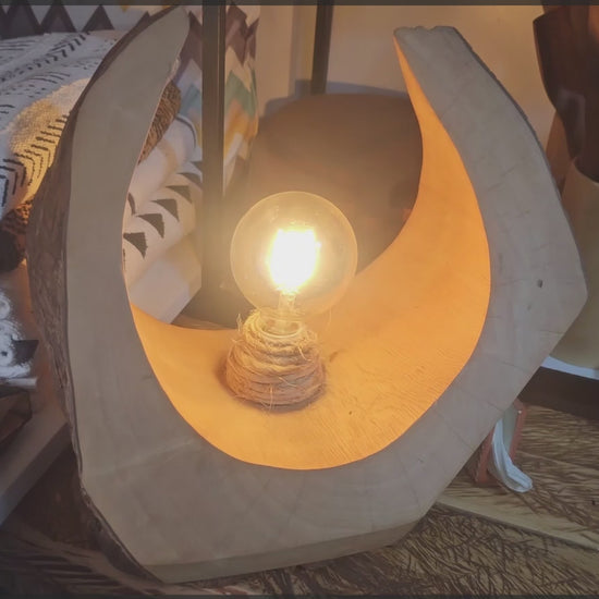 A wooden table lamp with a bulb made in rwanda
