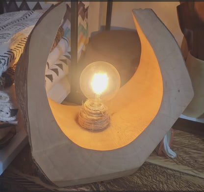 A wooden table lamp with a bulb made in rwanda