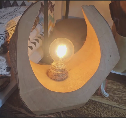 A wooden table lamp with a bulb made in rwanda